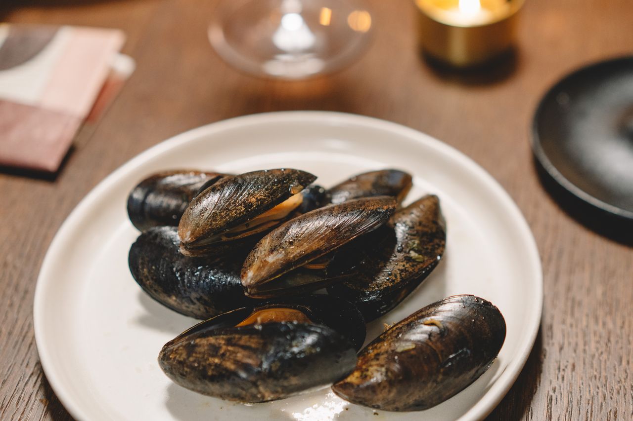 Close-up of delicious mussels on a white plate, perfect for gourmet dining themes.